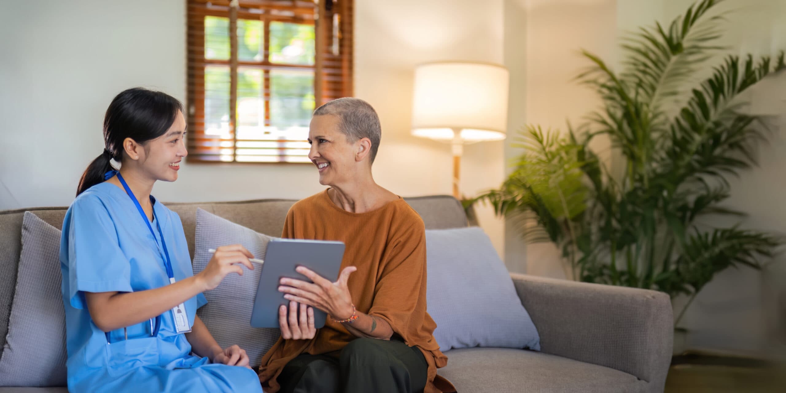 Caregiver with tablet consulting with an elderly client on a sofa